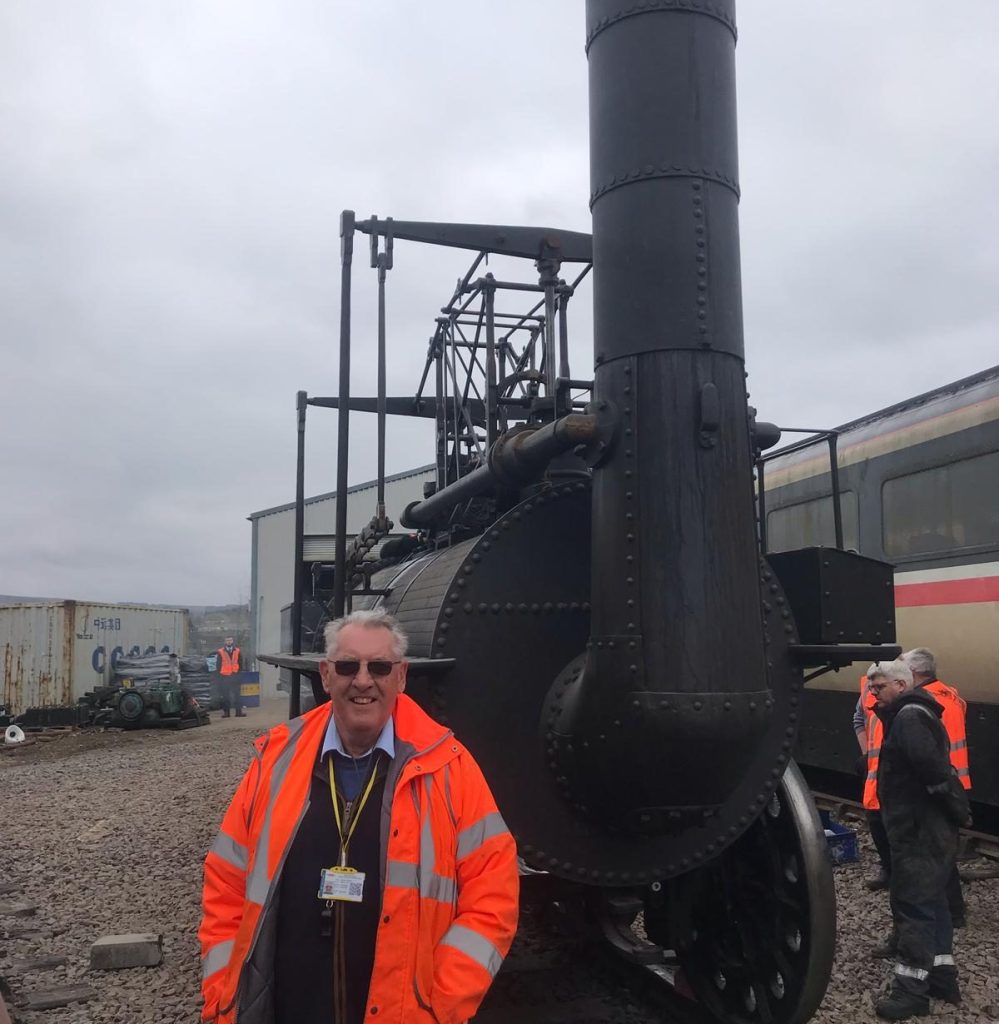 Team member wearing PPE standing in front of a locomotive.